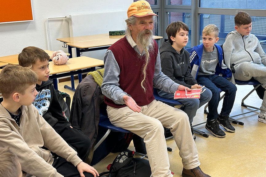 Der 78-jährige Jan mit dem langen Bart und der orangenen Cap sitzt mit wachem Blick in der Runde der Fünftklässler. Der ehemalige Obdachlose erzählt von seinem eintigen Leben.