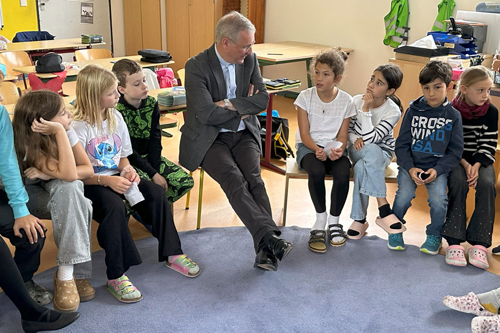 Schulbesuch von Erzbischof Stefan Heße an der Katholischen Schule Farmsen bei Zweitklässlern. Die Kinder sitzen mit dem Bischoff im Kreis.