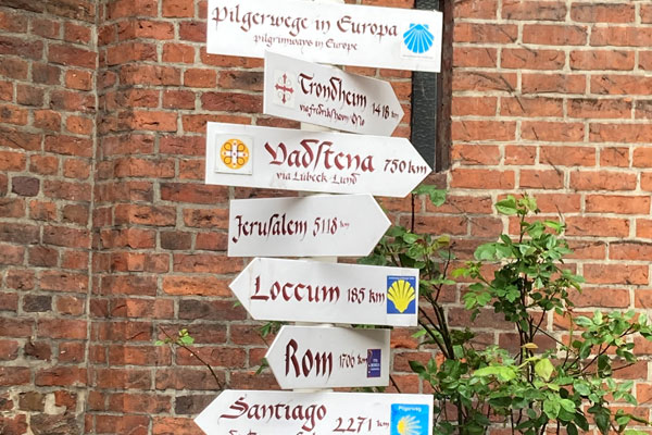 Unterwegs auf dem Jakobsweg - Hier sieht man einen Wegweiser mit vielen Schildern und Richtungen, die die Richtungen verschiedener Pilgerwege in Europe anzeigen.