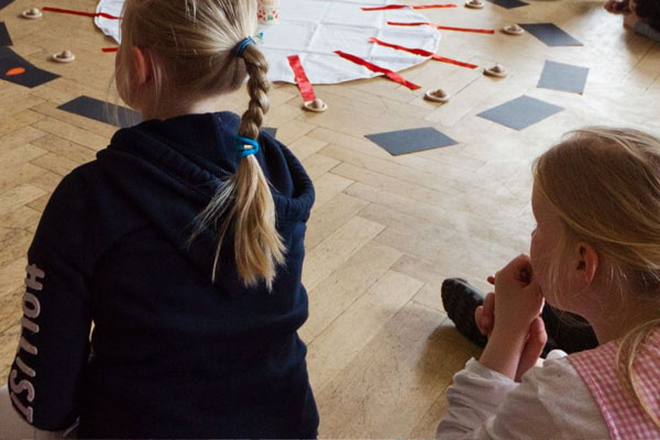 Hier sind Kinder zu sehen, die im Kreis auf dem Boden sitzen.